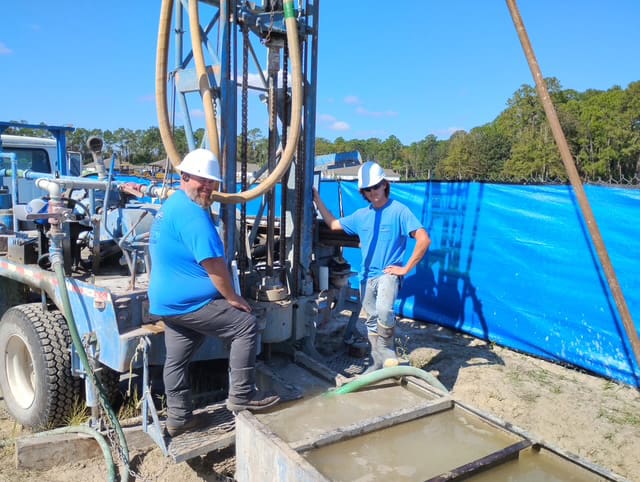 men-at-work1 2 Bronco Boys standing by a well drilling rig