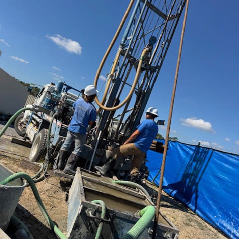 men-at-work3 2 Bronco Boys standing by a well drilling rig
